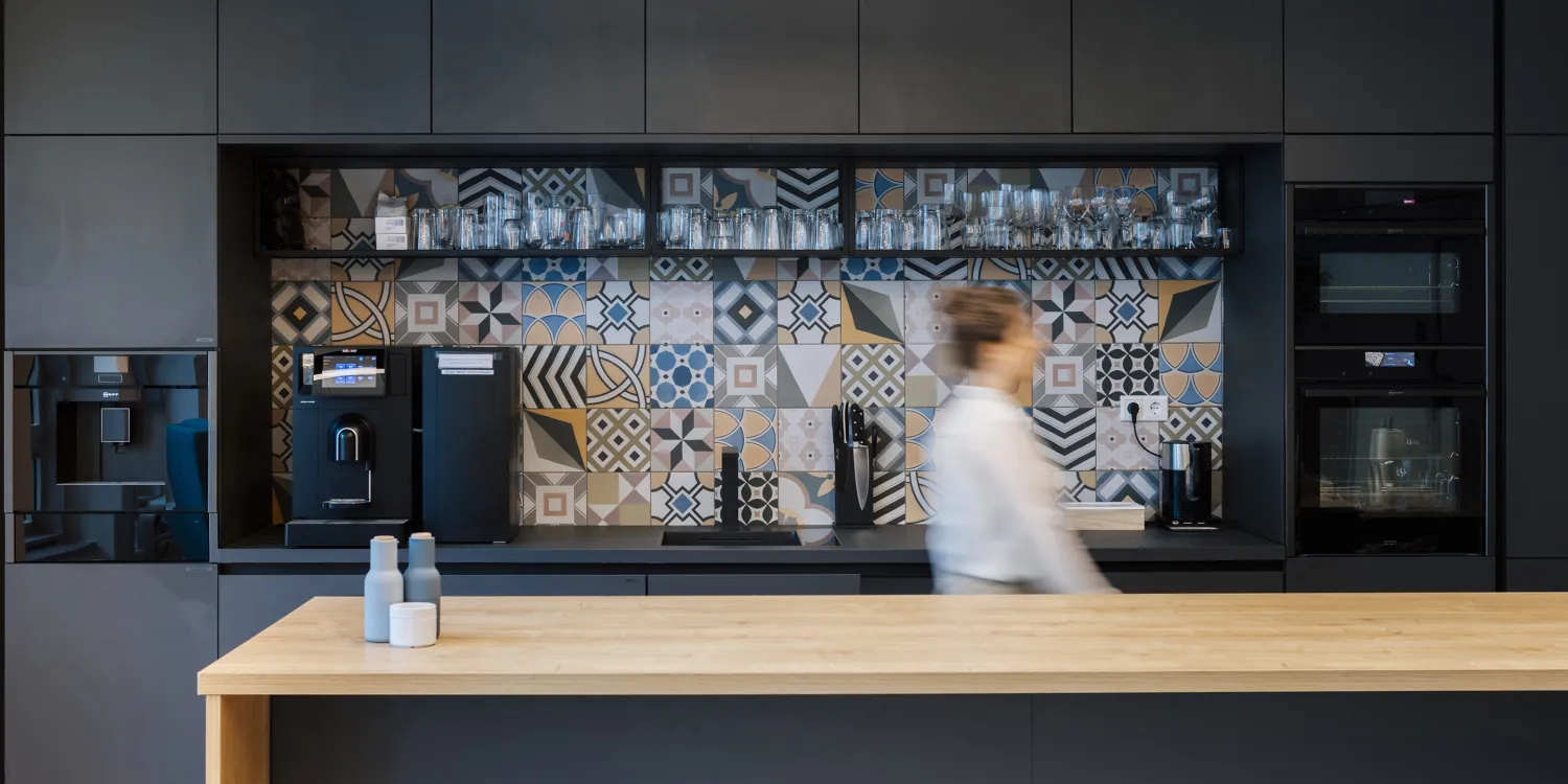 BSH – Stilvolle Kaffeebar mit dunkler Farbpalette, lebendigem Rückwand-Design und moderner Ausstattung.