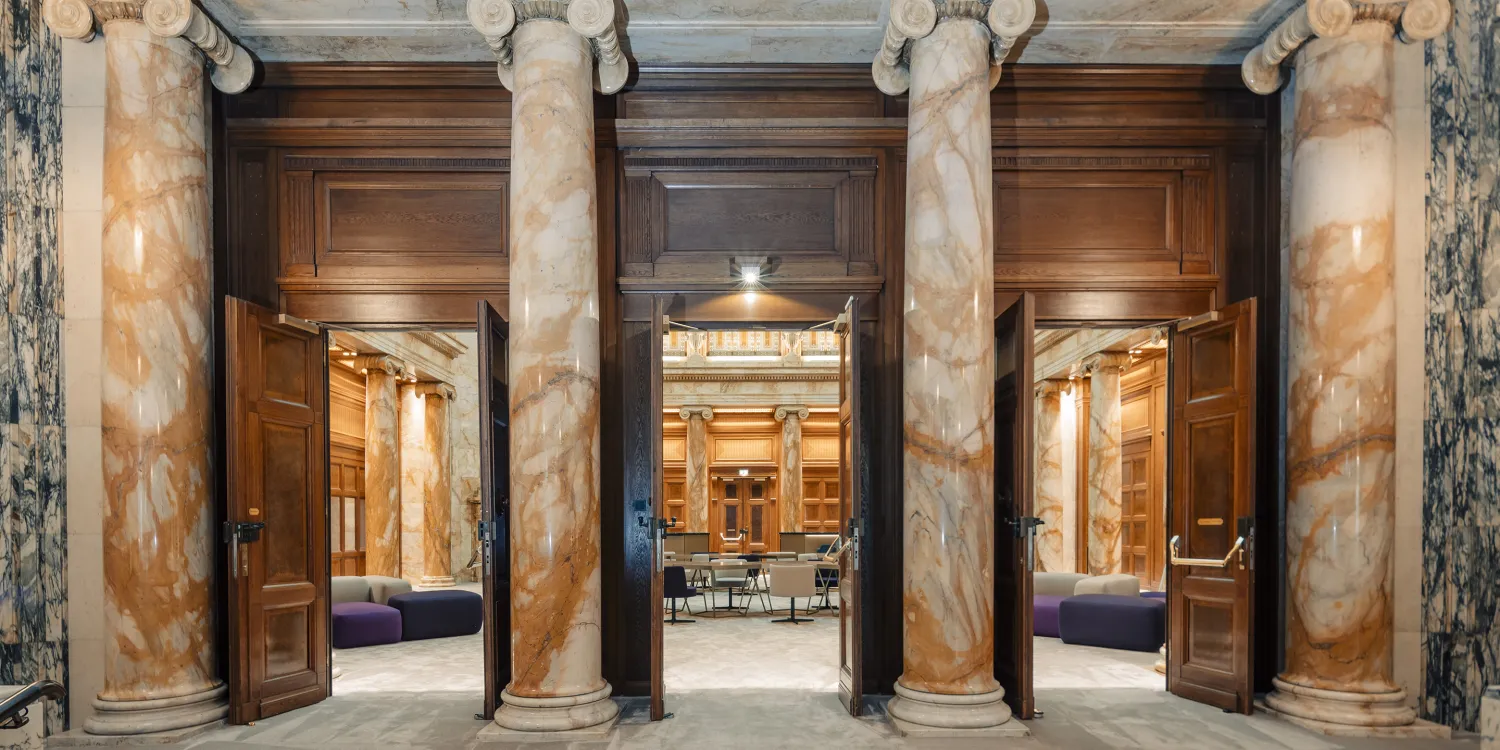 DLA Piper Wien: Eleganter Eingang mit Marmorsäulen, goldenen Türen und Blick in eine stilvolle Lobby.