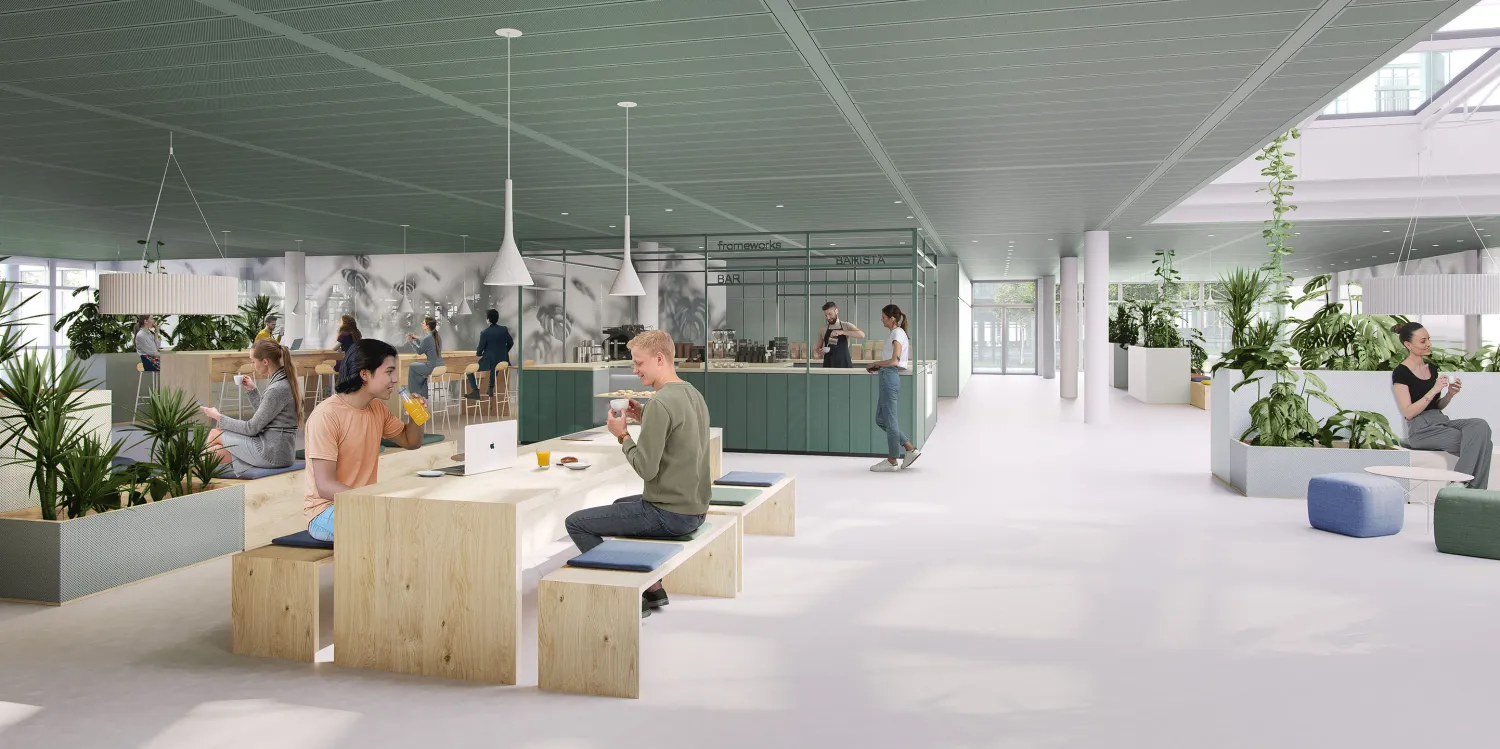 Einladende Kaffeebar im Frameworks mit begrünten Inseln, flexiblen Sitzbereichen und offener Raumgestaltung.