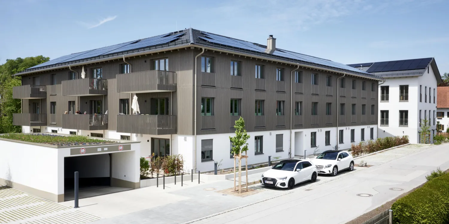 Moderne VR Bank Andechs mit Holzfassade, Solarpanelen auf dem Dach und heller, offener Gestaltung.