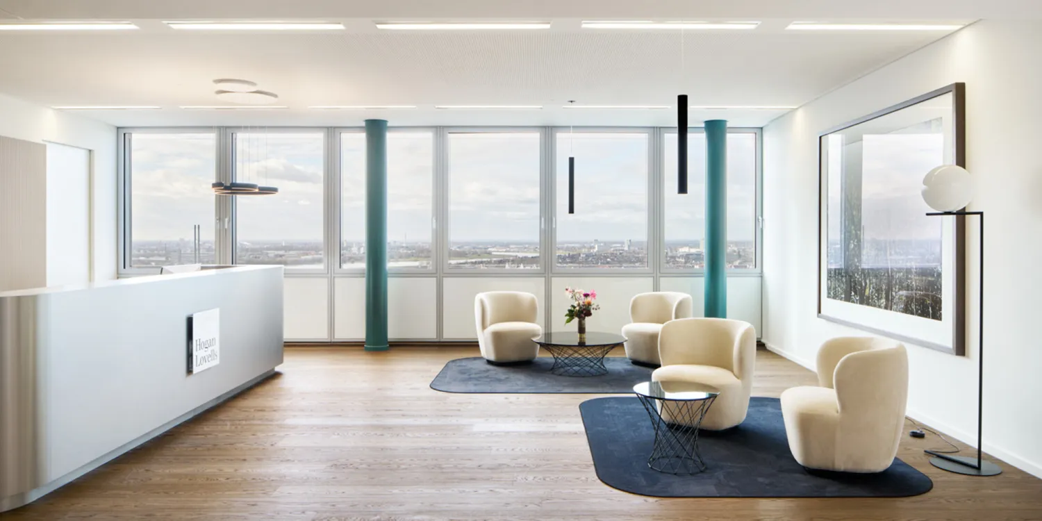 Hogan Lovells – Modernes New Work Büro mit Lounge-Bereich, Designer-Möbeln und Blick auf den Rheinturm.