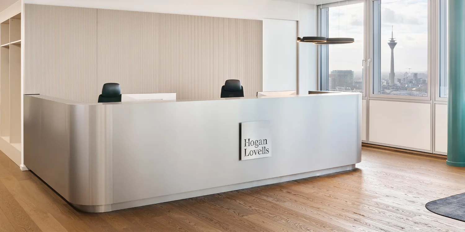 Hogan Lovells: Eine stilvolle Lounge mit beigen Sesseln, schwarzen Tischen, glänzenden Kugelleuchten und Stadtblick.