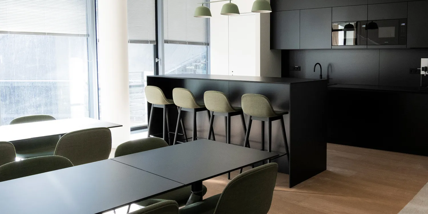 Moderne Küche mit Sitzmöglichkeiten an einer Bar. Die Hauptfarbe ist dunkelbraun.