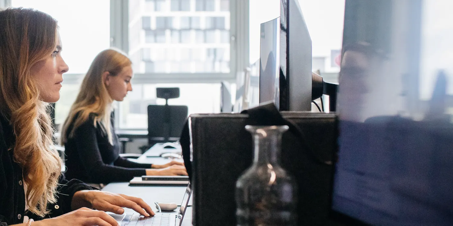 CSMM: Modernes Großraumbüro: Zwei Frauen sitzen vor einem Monitor und arbeiten.