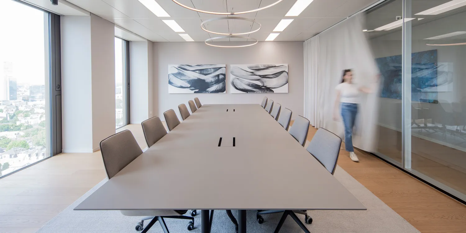 Ashurst: Minimalistischer Konferenztisch mit Ringleuchten und abstrakter Wandkunst