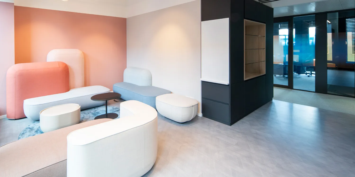 Maxon Follow – Loungebereich mit pastellfarbenen Polstermöbeln und minimalistischer Beleuchtung.