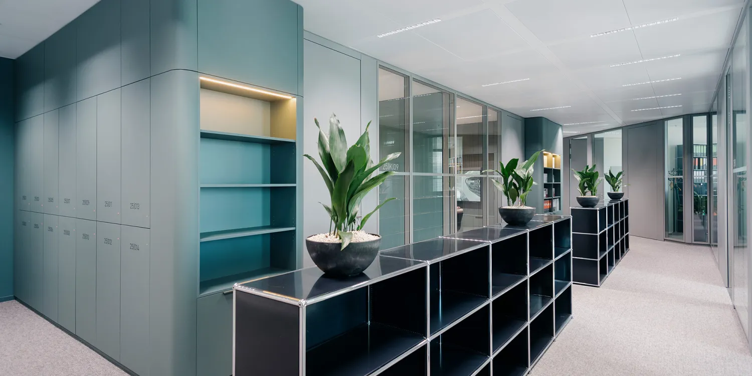 Allen & Overy – Bürointerieur: Blick in ein modernes Büro mit grüner Einbaumöblierung und Besprechungsraum in sanften Pastelltönen.