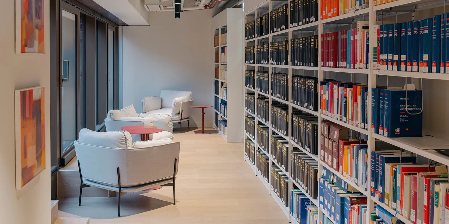 Ashurst München: raumhohes Bücherregal als Raumteiler und modernen Sitzmöbeln