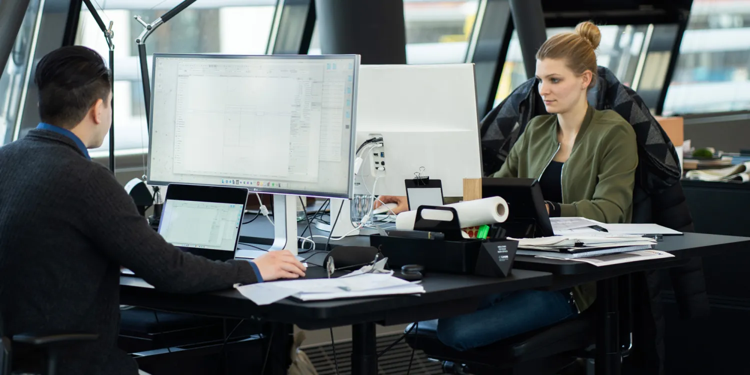 Mitarbeiter von CSMM sitzen vor einem Bildschirm im Büro und arbeiten.