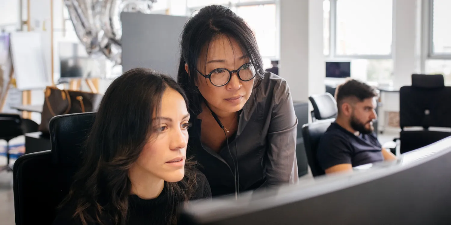 Mitarbeiter von CSMM stehen vor einem Screen und diskutieren