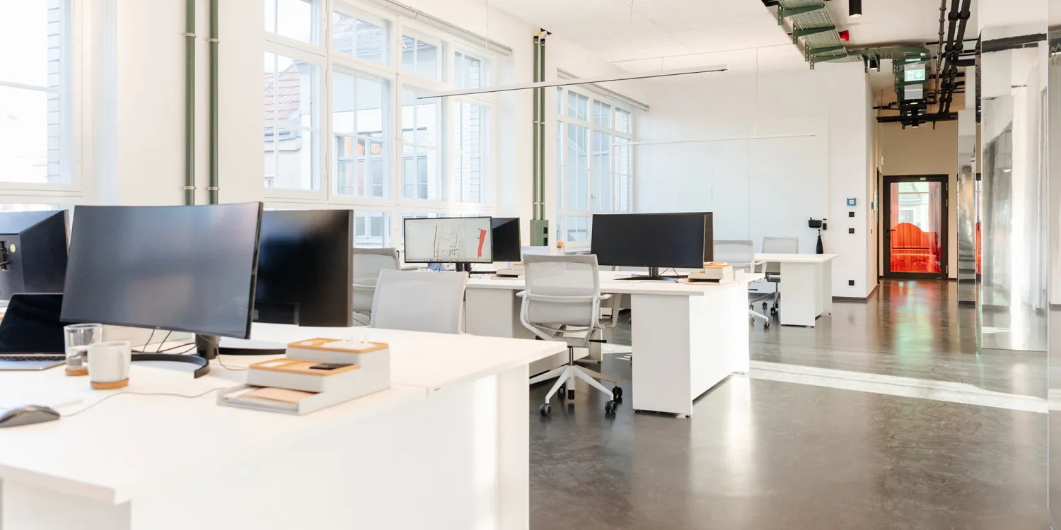 CSMM Berlin: Moderner Arbeitsraum, mit weissen Schreibtischen, hohen Fenstern und Monitoren