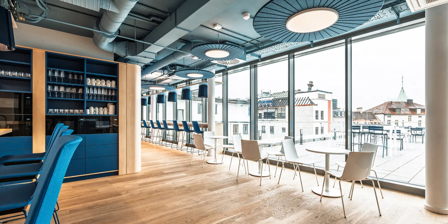 BFV Office4you – Lounge mit blauen Barhockern und offener Technikdecke