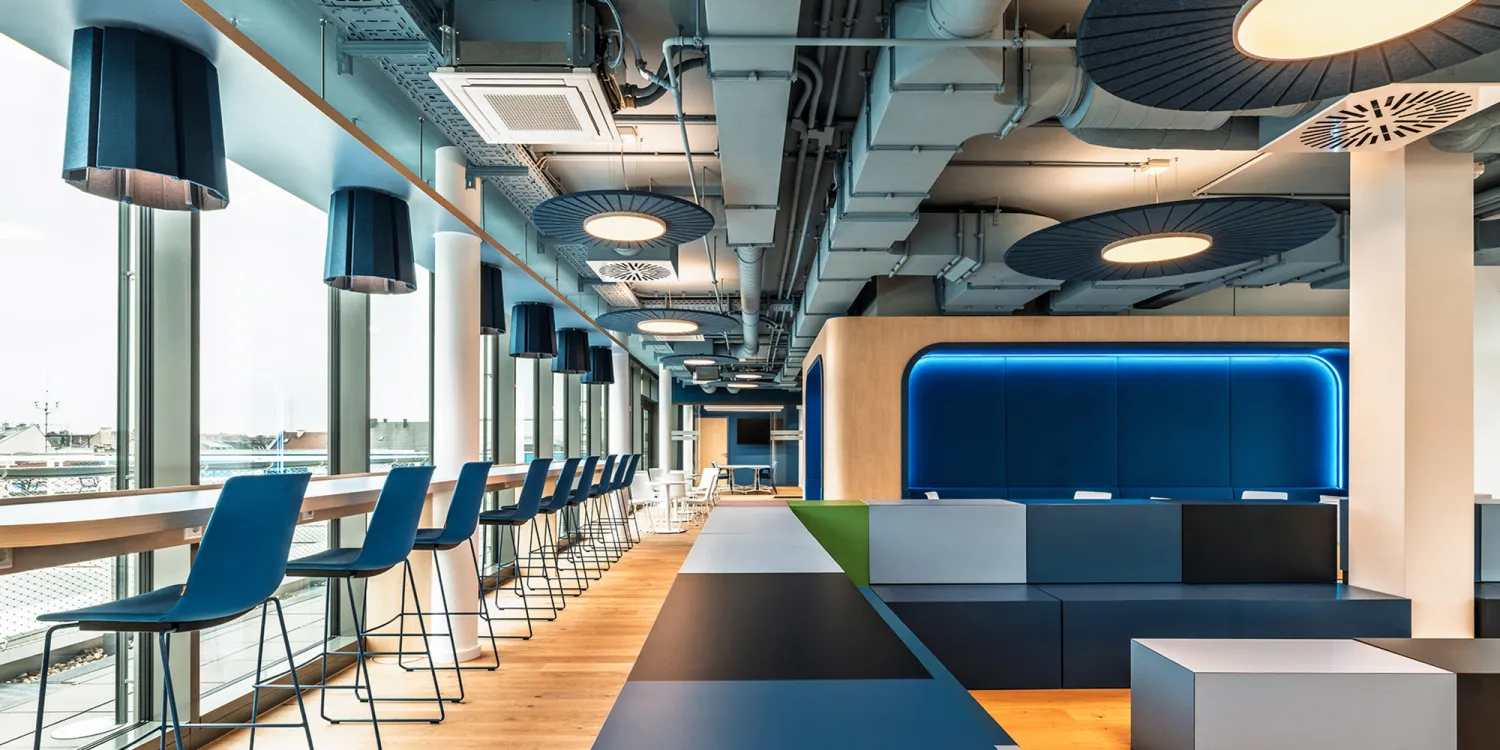 BFV Office4you – Lounge mit blauen Barhockern und offener Technikdecke