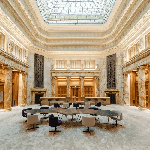 DLA Piper Wien: Elegante Halle mit Glasdach, Marmorsäulen, historischen Details und modernen Sitzmöbeln.