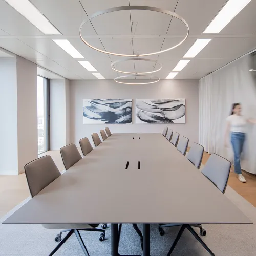 Ashurst: Minimalistischer Konferenztisch mit Ringleuchten und abstrakter Wandkunst