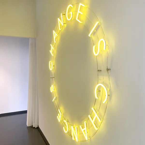 CSMM Berlin: Gelbe Neoninstallation 'CHANGE IS CHANCE' an einer weißen Wand im modernen Interior.