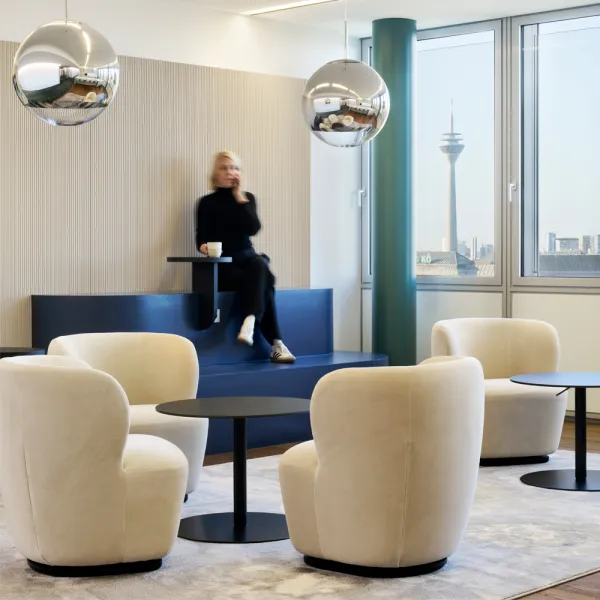 Hogan Lovells: Eine elegante Lounge mit beigen Sesseln, schwarzen Tischen, Spiegelkugelleuchten und Blick auf den Fernsehturm.