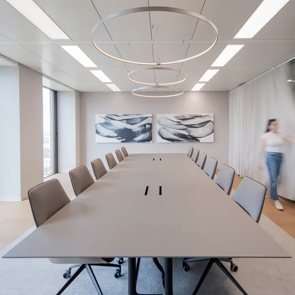 Ashurst: Minimalistischer Konferenztisch mit Ringleuchten und abstrakter Wandkunst