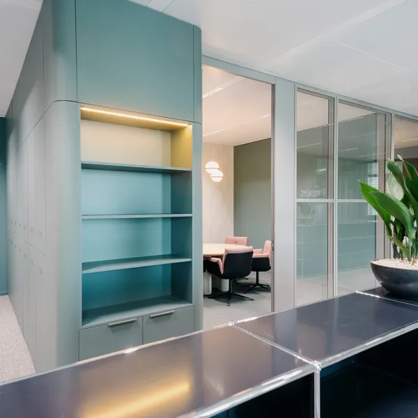 Allen & Overy – Bürointerieur: Blick in ein modernes Büro mit grüner Einbaumöblierung und Besprechungsraum in sanften Pastelltönen.