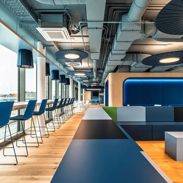 BFV Office4you – Lounge mit blauen Barhockern und offener Technikdecke