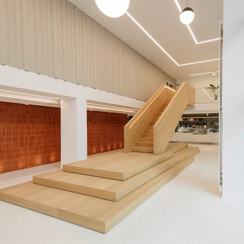 Kustermannpark – Skulpturale Holztreppe als zentrales Gestaltungselement in einer offenen Raumstruktur.