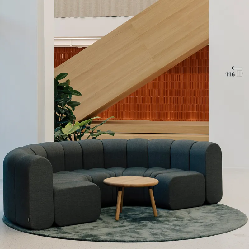 Kustermannpark – Elegante Lounge-Ecke mit geschwungenem Sofa, warmen Materialien und harmonischer Gestaltung.