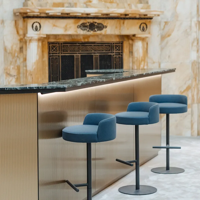 DLA Piper Wien: Elegante Bar mit goldener Theke, blauen Barhockern und edler Marmorwand.