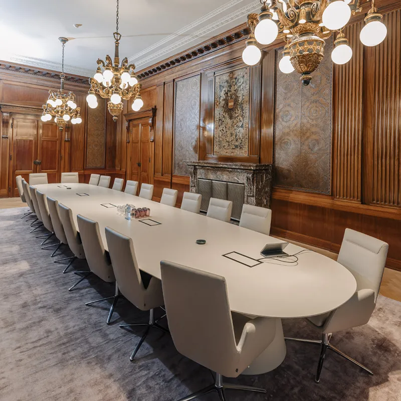 DLA Piper Wien: Historischer Konferenzraum mit Holzvertäfelung, elegantem ovalem Tisch und Kronleuchtern.