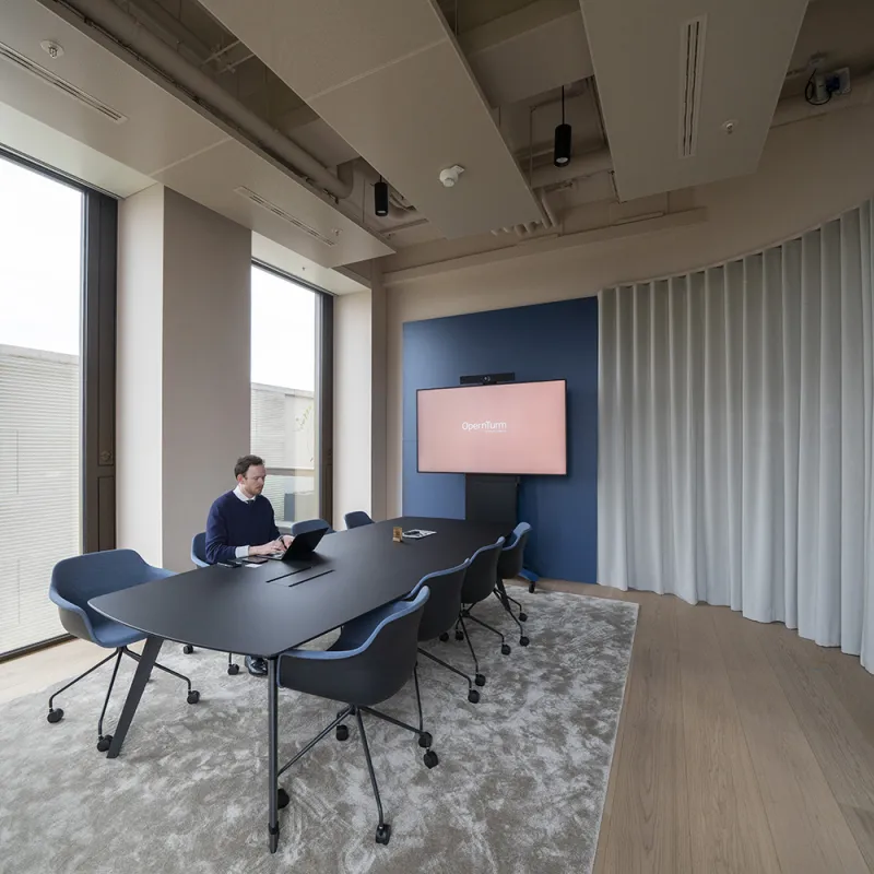 Moderner Meetingraum im Opernturm mit flexiblem Vorhangsystem, dunklem Konferenztisch und digitalen Tools.