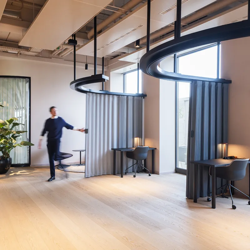 Flexible Arbeitsbereiche im Opernturm mit geschwungenen Vorhängen, Holzfußboden und natürlichem Licht.