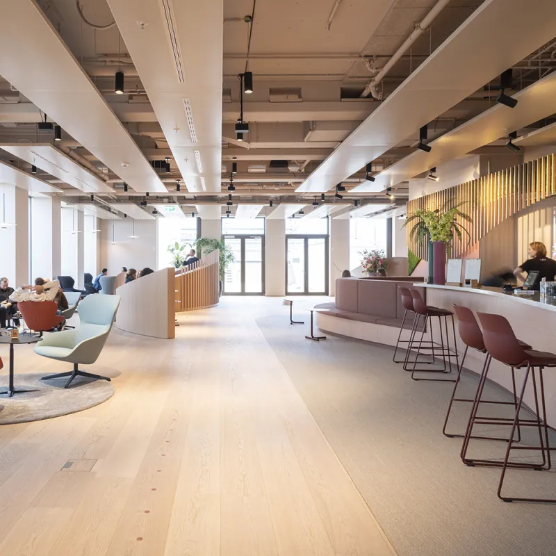 Offene Raumgestaltung mit fließenden Übergängen zwischen Lounge, Empfang und Café – einladend und dynamisch.