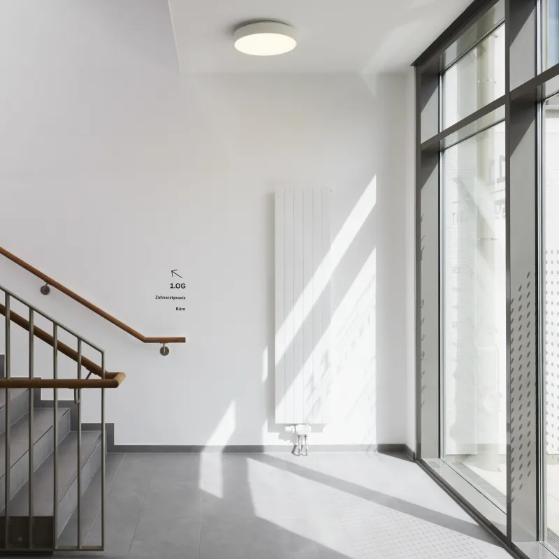 Lichtdurchflutetes Treppenhaus der VR Bank Andechs mit klaren Linien, Glasfassade und minimalistischer Gestaltung.