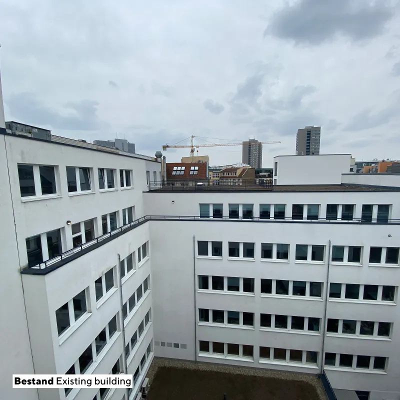 Innenhof des Projekts Quest mit weißer Fassadengestaltung, klaren Linien und urbanem Ausblick.
