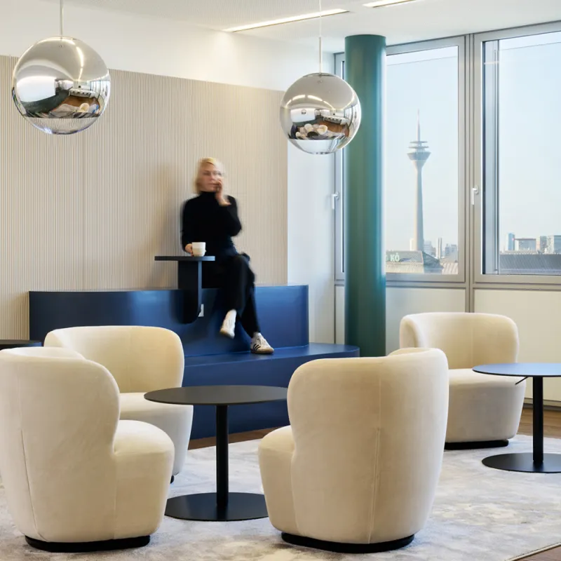 Hogan Lovells – Modernes New Work Büro mit Lounge-Bereich, Designer-Möbeln und Blick auf den Rheinturm.