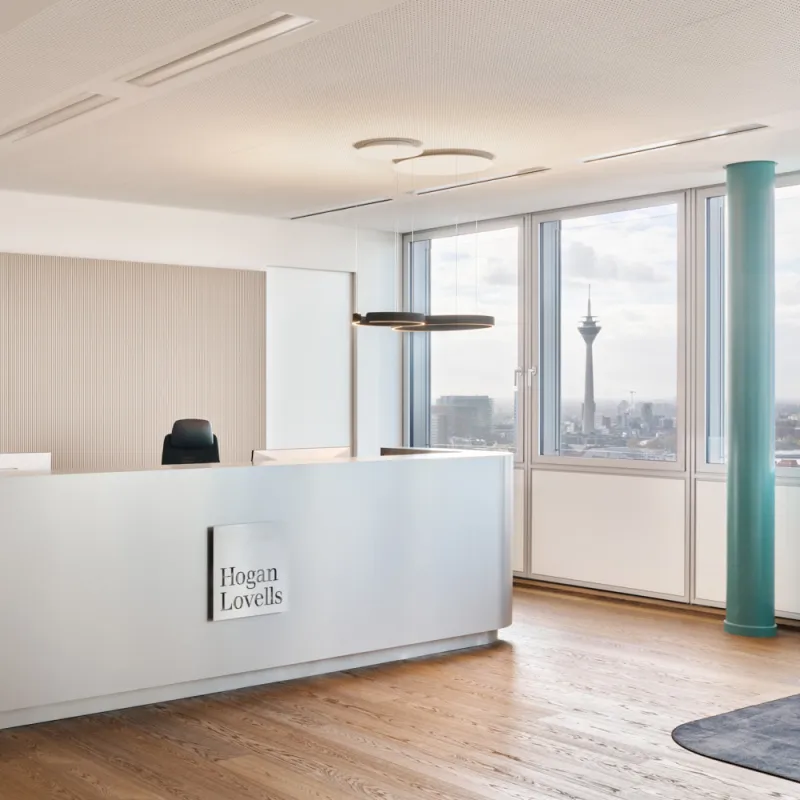Hogan Lovells – Empfangsbereich mit elegantem Design, Edelstahl-Theke und Panoramablick auf den Rheinturm.