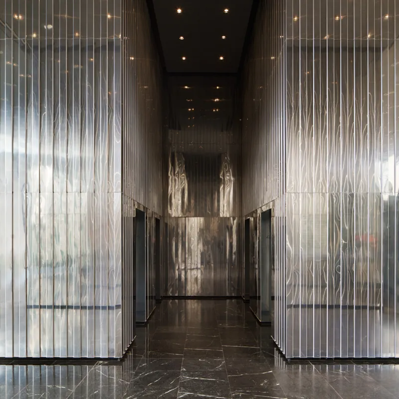 Hogan Lovells – Eleganter Eingangsbereich mit reflektierenden Metallwänden und dunklem Marmorboden.