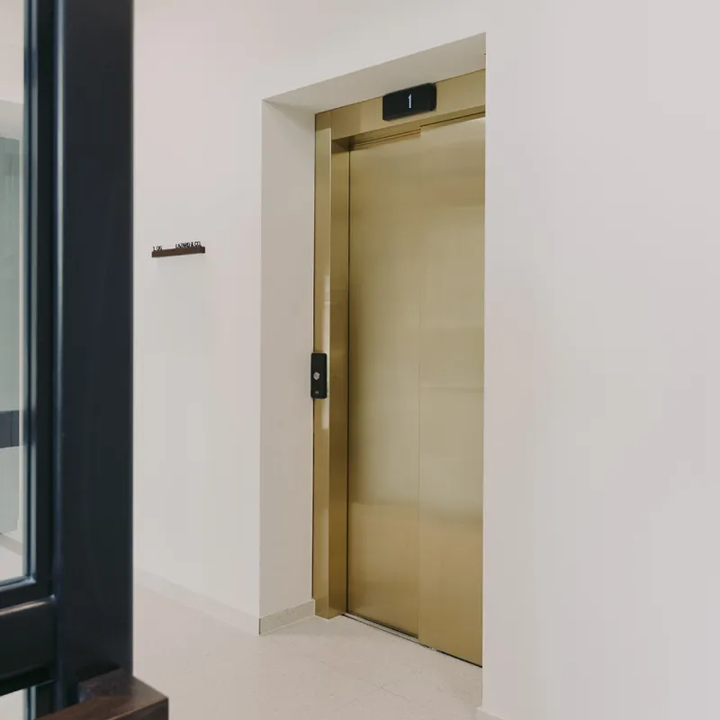 Leopoldstrasse – Edles Interior Design mit einem stilvollen goldfarbenen Aufzug in nachhaltiger Bürogestaltung.