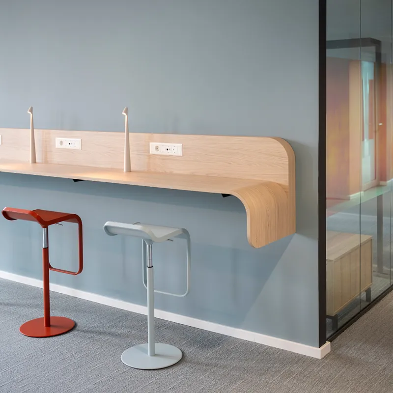 Maxon Follow – Schwebende Holztheke mit Designhockern und integrierter Stromversorgung.