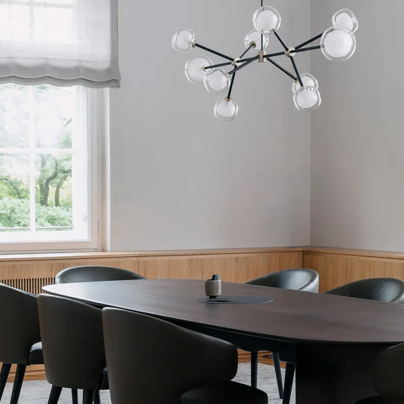 Eleganter Konferenzraum mit dunklem Tisch, schwarzen Sesseln und weißen Lampen.