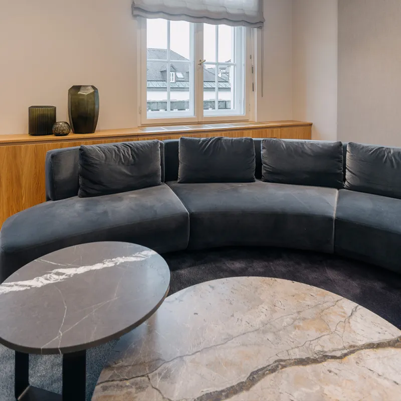 Eleganter Konferenzraum mit einer großen runden Couch und Marmortischen im Vordergrund.