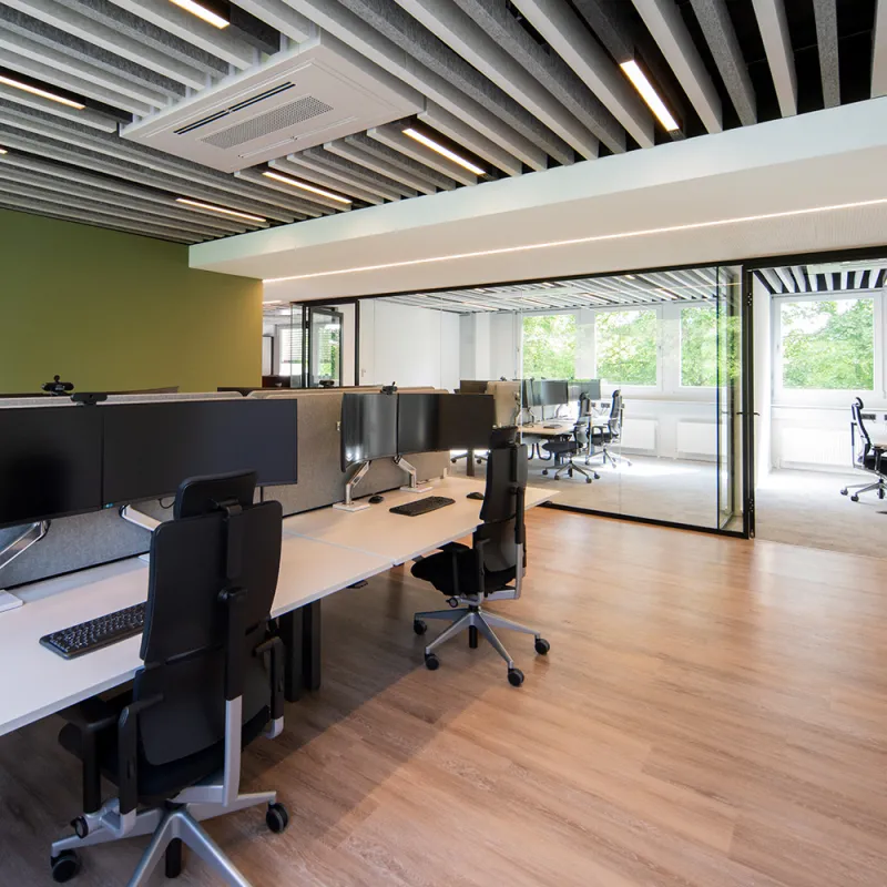 Energieunternehmen: Offener Arbeitsplatzbereich mit Glaswänden und modernen Monitor-Setups.