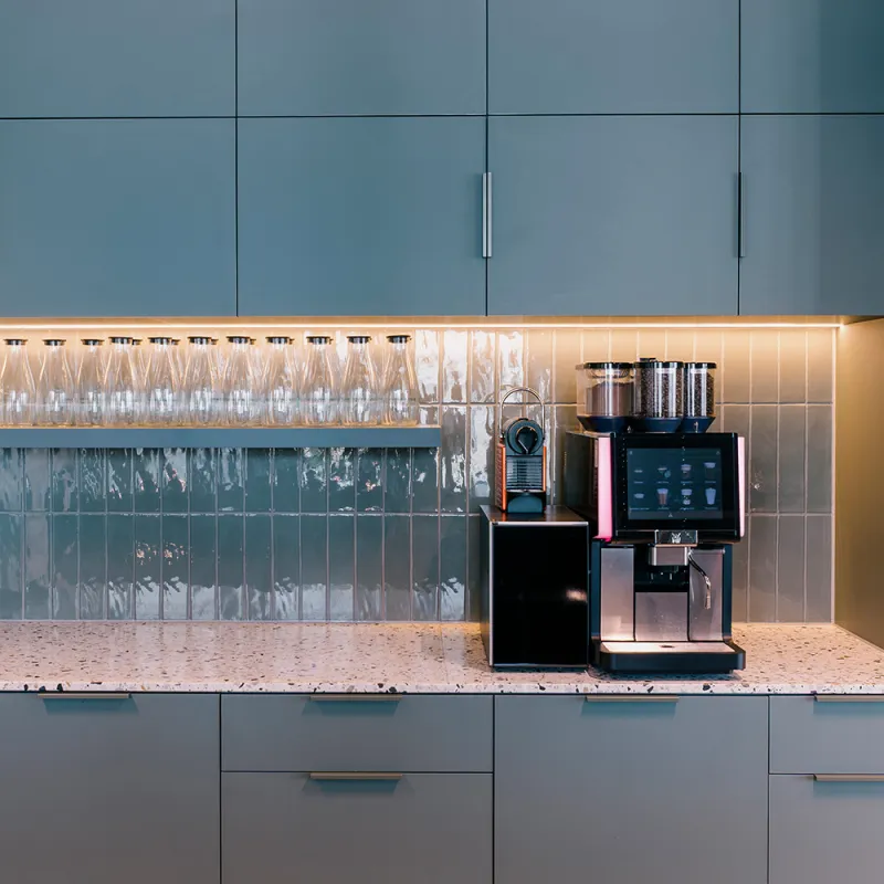 Wirtschaftskanzlei: Moderne Küchenzeile mit Espresso Maschine und Hängeschränke.