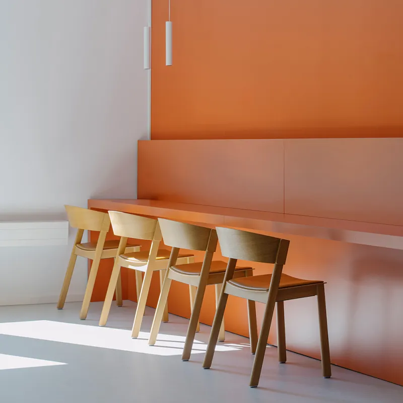 Elsenheimerstraße – orangene Wand mit Ablage und Holzstühlen