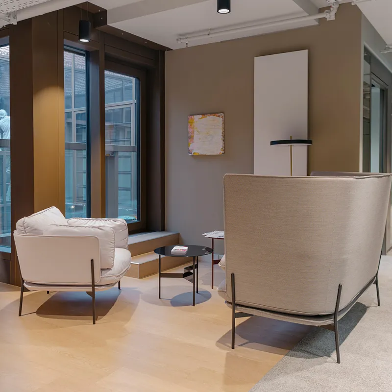 Ashurst München: moderne Sitzecke mit hellen Polstermöbeln und Glaswand im Hintergrund