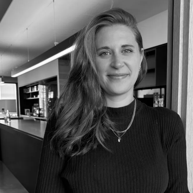 Nicole Kindshofer als neue Junior Architektin lehnt an einem Türrahmen und lächelt in die Kamera