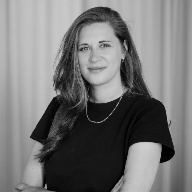 Nicole Kindshofer als neue Junior Architektin lehnt an einem Türrahmen und lächelt in die Kamera